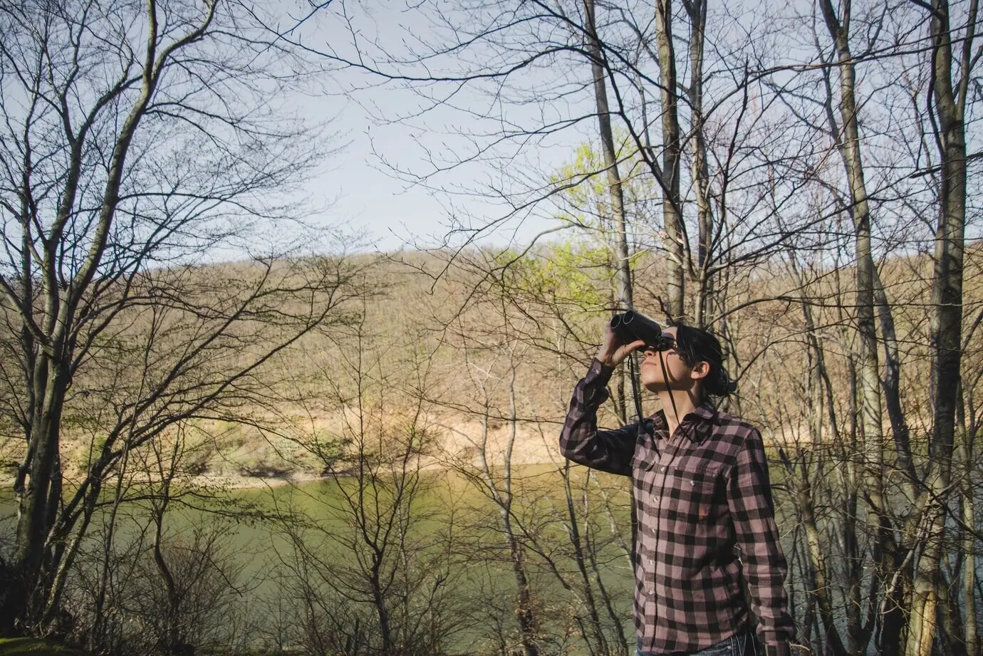 Ein Wanderer mit Fernglas im Wald